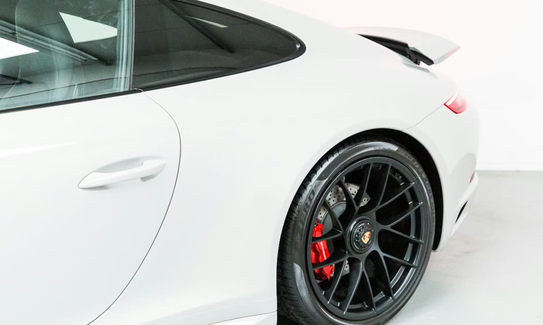 The flank of a white sports car showing the door, door handle, rear quarter panel and front wheel